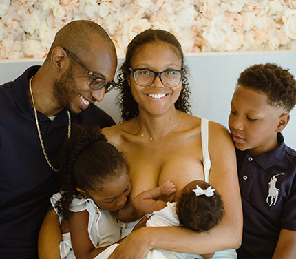 Mother breastfeeding with family around her